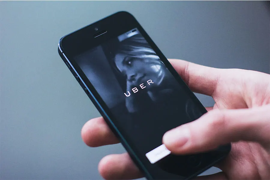 persons hand holding a smartphone with the uber app login page shown